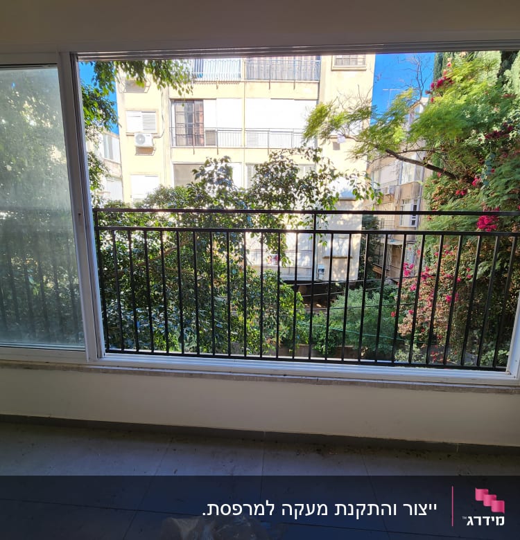 חלון גדול עם מסגרת מתכת ונוף ירוק